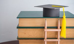 Graduation,Cap,On,Textbooks,With,Pencil,Ladder,In,Classroom,Background