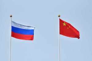 Russian and Chinese flag, symbol of friendship. China and Russia flag waving in the wind against white cloudy blue sky together. Diplomacy concept, international relations.