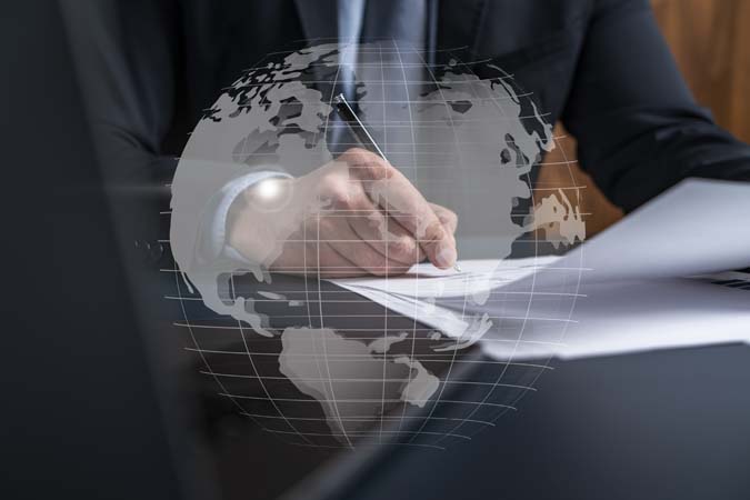 Businessman,In,Suit,Signs,Contract.,Double,Exposure,With,World,Map