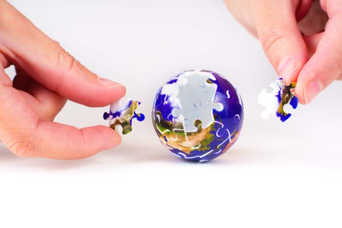 Two,Hands,Working,On,A,Colorful,Puzzle,Globe,,Symbolizing,Collaboration